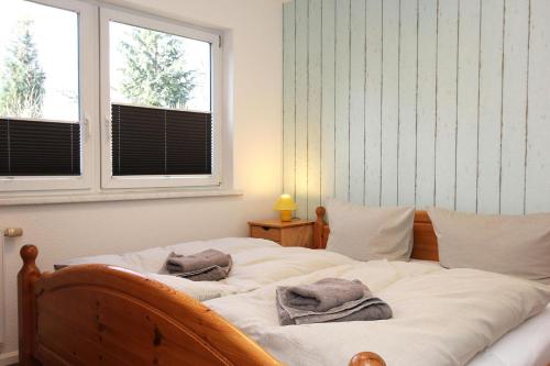 two beds in a bedroom with two windows at Lieblingshaus Eddie in Prerow
