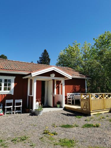 a small red house with a porch and a yard at Idyllisk nybyggd stuga på Sollerön. in Sollerön