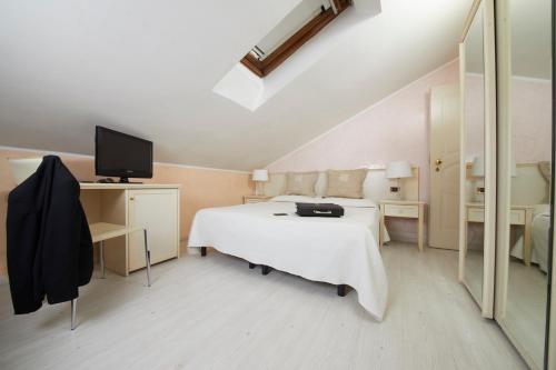 a bedroom with a white bed and a television at Hotel Vienna Ostenda e Ristorante il Danubio in Rimini