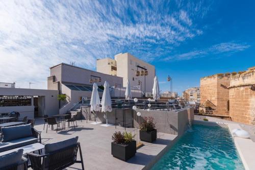 um pátio no último piso com uma piscina, cadeiras e guarda-sóis em Catedral Almería em Almeria