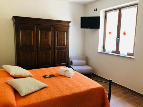 1 dormitorio con 1 cama con manta naranja y silla en Agriturismo LA VECCHIA CASCINA, en Filattiera