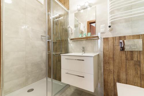 a bathroom with a shower and a sink and a mirror at Astra Apartments in Oświęcim