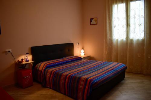 a bedroom with a bed with a striped blanket and a window at tra il borgo e il mare in Cervo