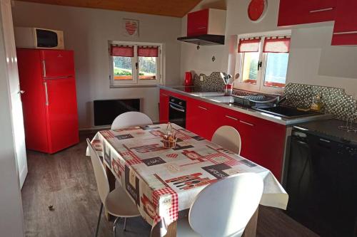 a kitchen with red cabinets and a table with white chairs at Le Chalet du bonheur , individuel avec belle vue in Laveline