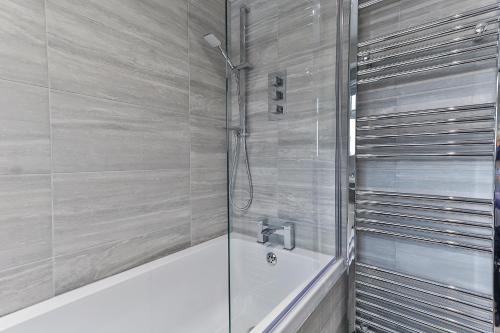 y baño con ducha, bañera y bañera. en Newly Renovated 3 Bed Apartment with Parking by Ark SA en Sheffield