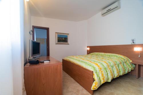 a bedroom with a bed and a television on a table at Bonsai B&B Alghero in Santa Maria la Palma