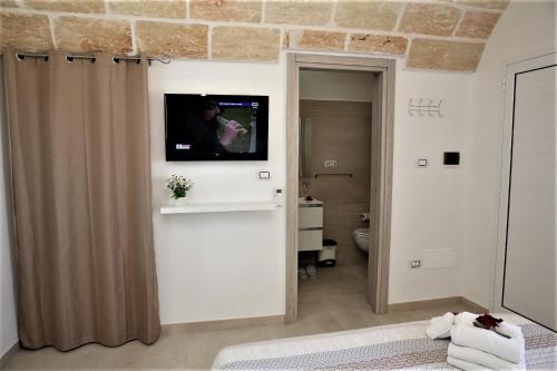 a bathroom with a television on a wall with a toilet at Villa Stella in Marina di Pescoluse