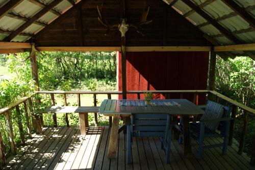 a table and chairs on a deck with a gazebo at Karlsäter - Stora stugan in Älvkarleby