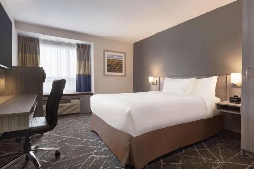 a hotel room with a large bed and a desk at Microtel Inn & Suites by Wyndham Lloydminster in Lloydminster