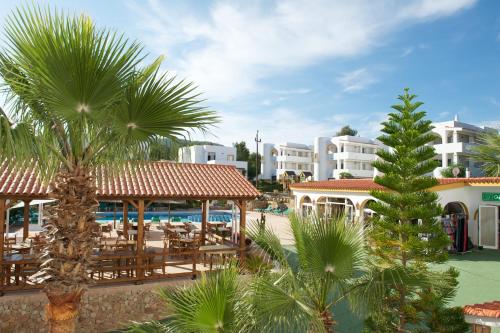 a view of a resort with a palm tree at Apartamentos Blanco Sol in Cala Vadella