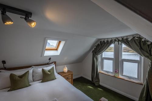 a bedroom with a white bed and two windows at The Lodge in the Loch in Portree