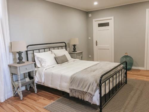 a bedroom with a bed with white sheets and a door at Quinta Costa da Estrela in Gouveia