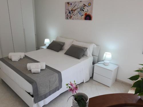 Appartamento MariaLuisa في مارسالا: غرفة نوم بيضاء مع سرير أبيض كبير مع طاولتين