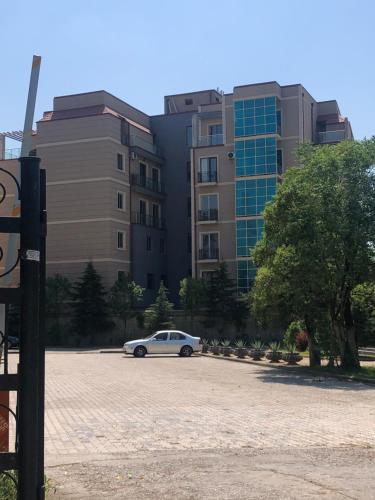 a white car parked in a parking lot in front of a building at Wellconect in Kutaisi