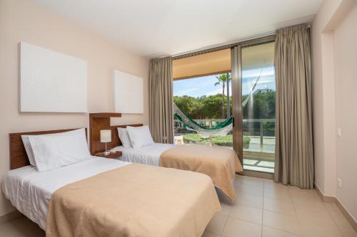 a hotel room with two beds and a balcony at Apartamentos Vila das Lagoas – Salgados in Guia