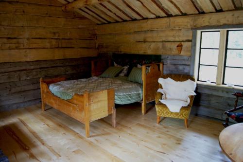 a bedroom with a bed and chairs in a log cabin at Karlsäter - Timmerstugan in Älvkarleby