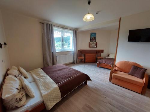 a bedroom with a bed and a chair and a window at Agal Zieleniec in Zieleniec