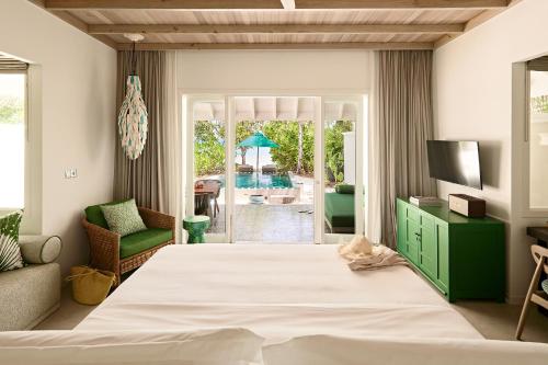 a bedroom with a large bed and a living room at Finolhu, A Seaside Collection Resort, a Member of Design Hotels in Baa Atoll