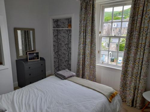 1 dormitorio con 1 cama y una ventana con cortinas en Burntisland Garden Apartment, Fife - 40 mins to Edinburgh en Burntisland