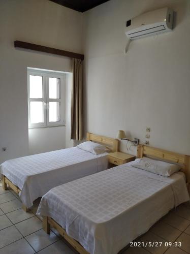 duas camas num quarto de hotel com uma janela em Paradisos Kastellorizou em Meyisti