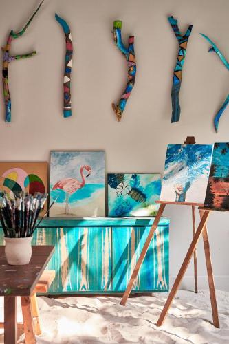 a room with paintings on a wall with a table at Finolhu, A Seaside Collection Resort, a Member of Design Hotels in Baa Atoll