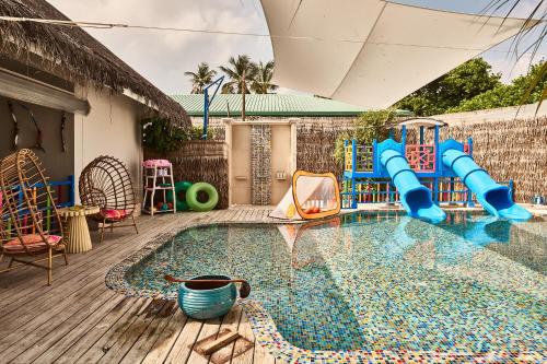 a pool with a water slide in a backyard at Finolhu, A Seaside Collection Resort, a Member of Design Hotels in Baa Atoll