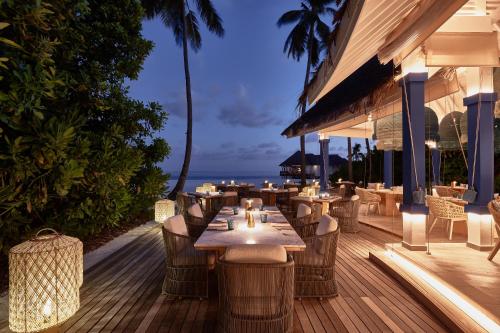 a restaurant with tables and chairs on a deck at Finolhu, A Seaside Collection Resort, a Member of Design Hotels in Baa Atoll