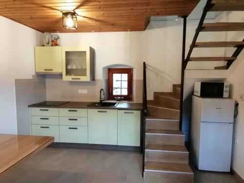 uma cozinha com armários brancos e uma escadaria com um micro-ondas em Hiša pod Gradičem em Kobarid