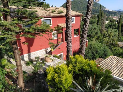 una casa roja con árboles delante de ella en Kontos Mansion, en Benitses