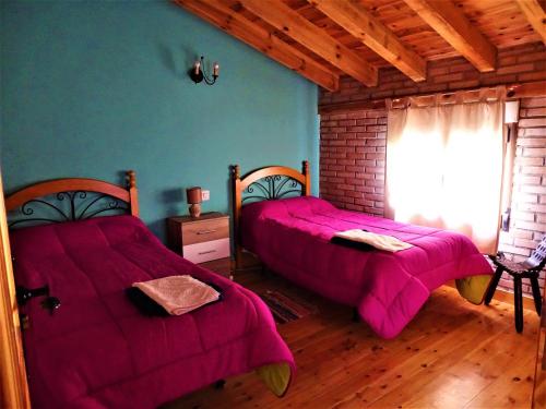 2 łóżka w pokoju z fioletowymi kocami w obiekcie Hostal Camino Del Cid w mieście Huerta del Rey