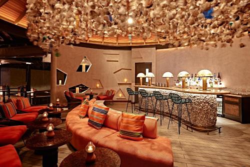 a hotel lobby with couches and a bar with a counter at Finolhu, A Seaside Collection Resort, a Member of Design Hotels in Baa Atoll