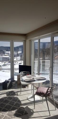 a living room with a table and chairs and windows at Apartament 25 Czarna Góra nr 5 Ischgl in Sienna