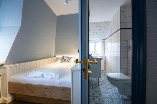 a small bedroom with a bed and a toilet at Ual Öömrang Wiartshüs in Norddorf