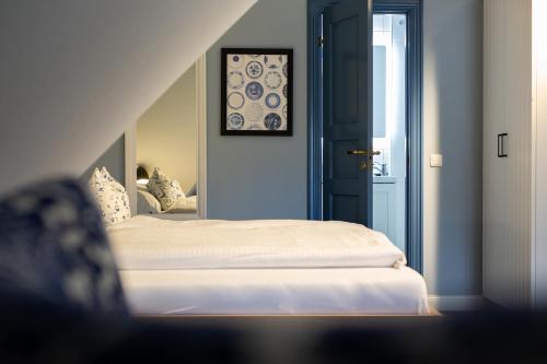 a bedroom with a white bed and a mirror at Ual Öömrang Wiartshüs in Norddorf