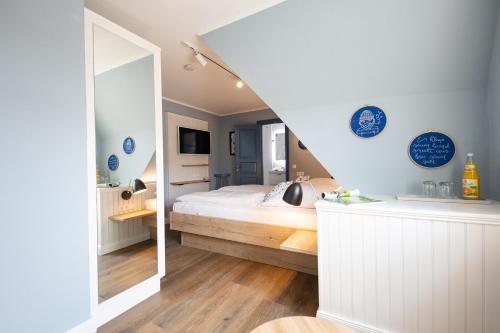 a bedroom with a white bed and a mirror at Ual Öömrang Wiartshüs in Norddorf