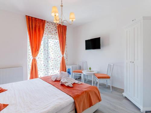 a bedroom with a bed with orange curtains and a table at Pensiunea Casuta cu Trandafiri 2 in Slănic