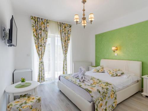 1 dormitorio con cama blanca y pared verde en Pensiunea Casuta cu Trandafiri 2 en Slănic
