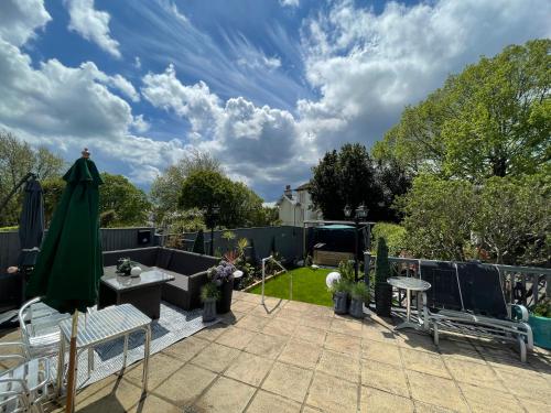 a patio with chairs and a green umbrella at The Southbourne Villa in Torquay