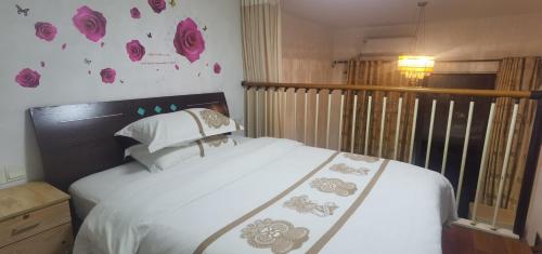 a bedroom with a white bed with pink flowers on the wall at Guangzhou Victory Apartment in Guangzhou
