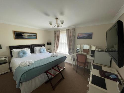 a bedroom with a bed and a desk and a television at The Southbourne Villa in Torquay