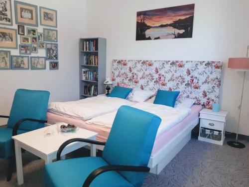 a bedroom with a bed and two blue chairs at Ubytovanie u Marty in Veľký Meder