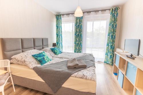 1 dormitorio con 1 cama grande y cortinas azules en Maritima, en Krynica Morska