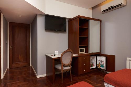 
a room with a bed, chair, desk and a television at Altos de Guemes Hotel in Mar del Plata
