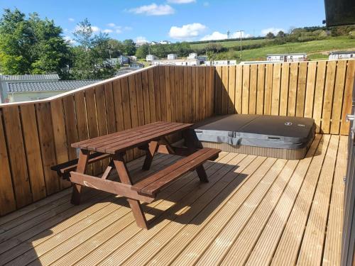 a wooden deck with a picnic table and a bed at Sunnyvale Holiday Park in Saundersfoot