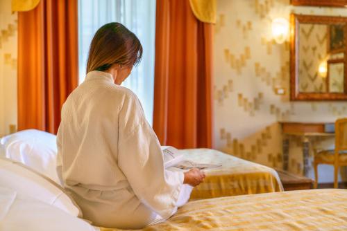 a woman sitting on a bed in a hotel room at Hotel La Rosetta in Perugia
