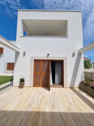 a white house with a wooden door at Apartments Leticia in Vrsi