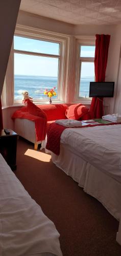 エクスマウスにあるAsh Hotel B&Bのベッドルーム1室(ベッド2台付)、海の景色を望む窓が備わります。