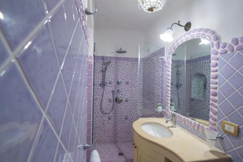 Baño púrpura con lavabo y espejo en Casa Giulia - sophisticated apartment with view, en Positano