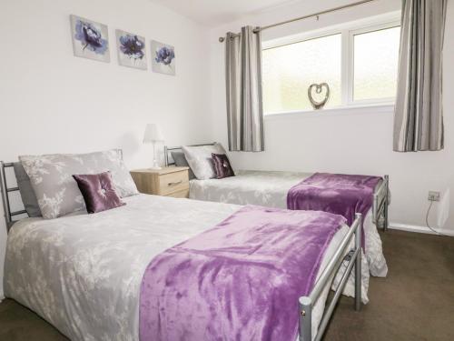 two beds in a bedroom with purple sheets at 13 Manorcombe Bungalows in Callington