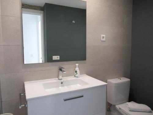 a bathroom with a sink and a mirror and a toilet at La Rosita Sun Apartments, by Comfortable Luxury in Corralejo